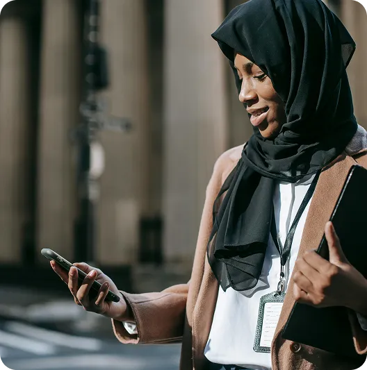 Migrant woman checking her phone while commuting, representing everyday heroes who support loved ones abroad
